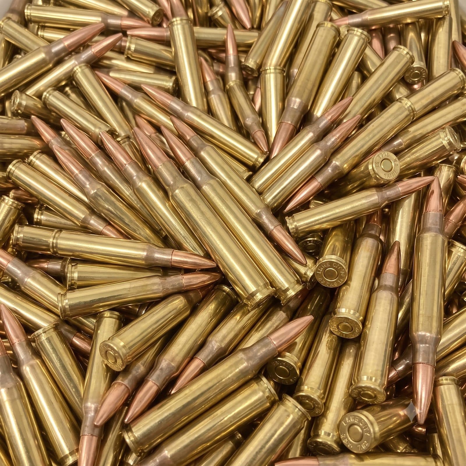 A bed of loose bottlenecked rifle cartridges, brass cases with copper jacketed bullets